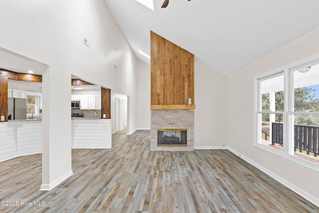 unfurnished living room featuring ceiling fan, light hardwood / wood-style flooring, and high vaulted ceiling