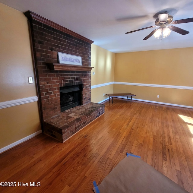 unfurnished living room with ceiling fan, wood-type flooring, and a brick fireplace