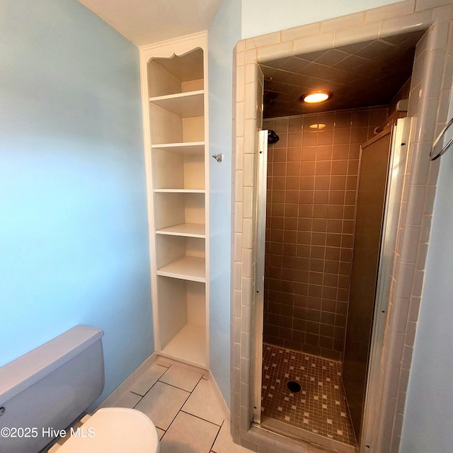 bathroom featuring tile patterned flooring, built in features, a shower with door, and toilet