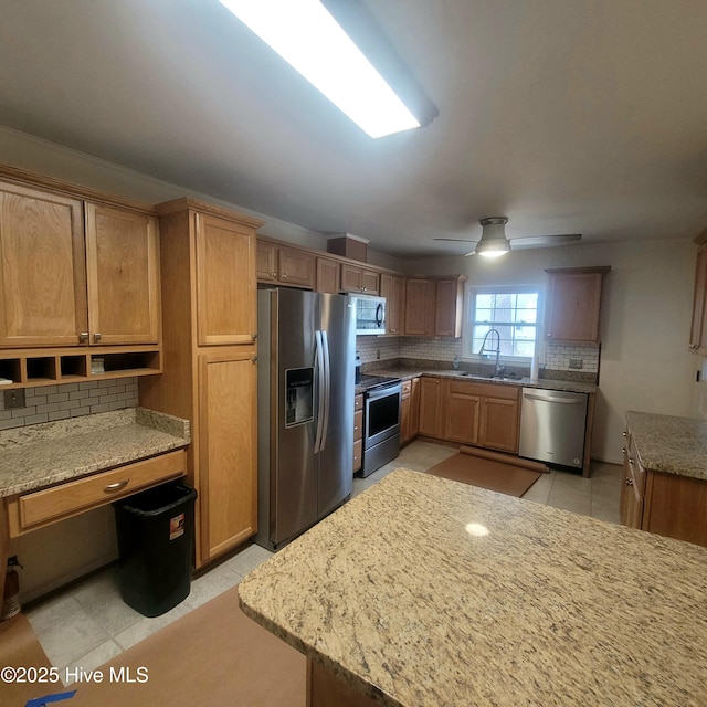 kitchen with sink, backsplash, ceiling fan, stainless steel appliances, and light stone countertops