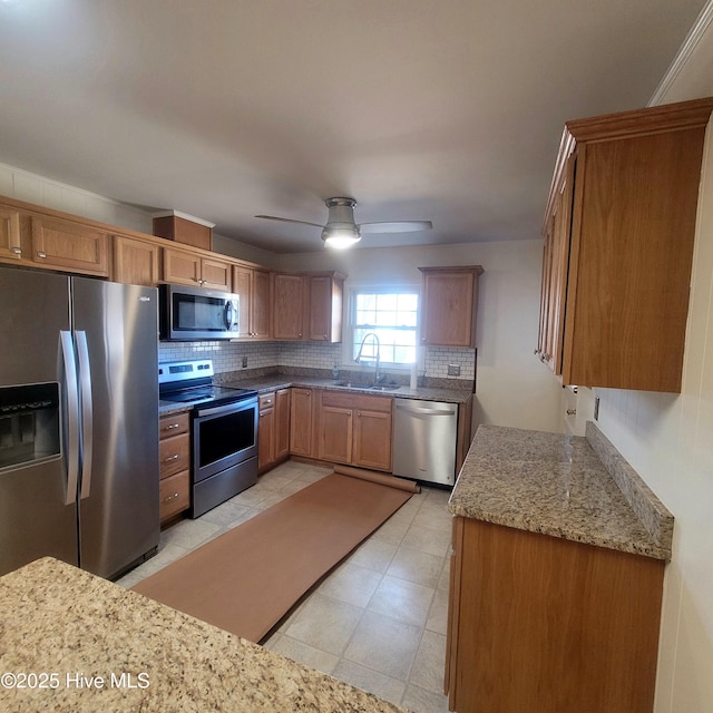 kitchen featuring sink, ceiling fan, stainless steel appliances, light stone countertops, and decorative backsplash