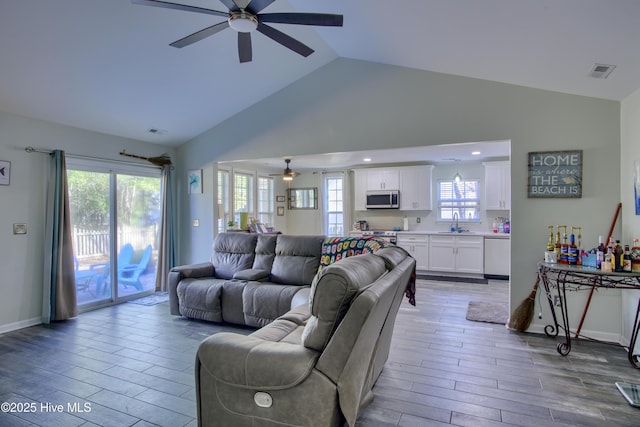 living room with ceiling fan, sink, and vaulted ceiling