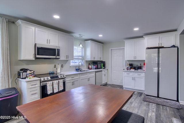 kitchen with appliances with stainless steel finishes, light hardwood / wood-style floors, white cabinets, and sink