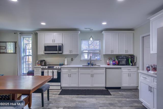 kitchen with hanging light fixtures, white cabinets, sink, and stainless steel appliances