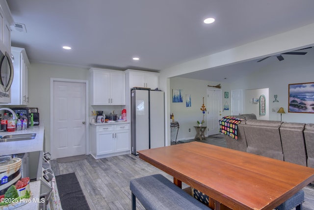 kitchen with white fridge, white cabinetry, light hardwood / wood-style floors, ceiling fan, and sink