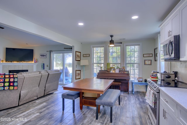 dining area with ceiling fan, a tile fireplace, and light hardwood / wood-style flooring