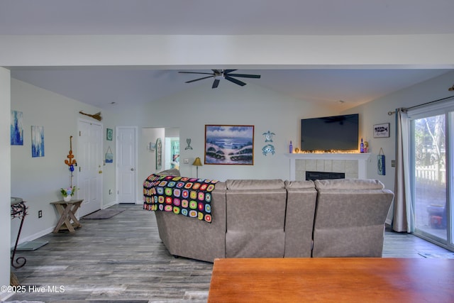 living room featuring ceiling fan, wood-type flooring, lofted ceiling, and a fireplace