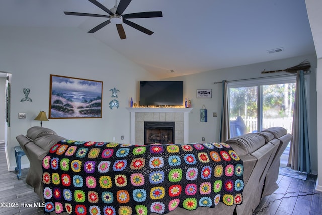 living room featuring hardwood / wood-style flooring, vaulted ceiling, ceiling fan, and a fireplace