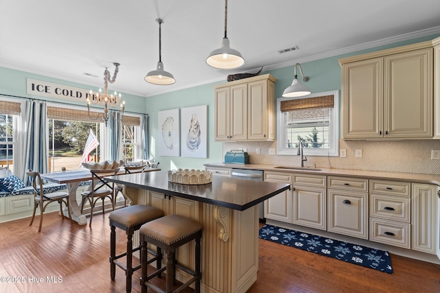 kitchen featuring sink, cream cabinets, pendant lighting, a kitchen island, and a breakfast bar area