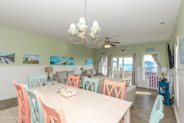 dining space featuring ceiling fan with notable chandelier and hardwood / wood-style flooring