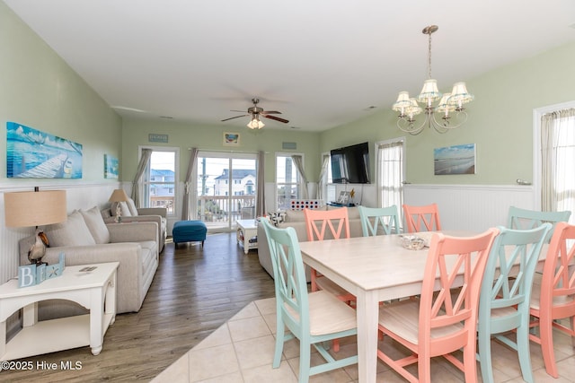 dining space with light tile patterned floors and ceiling fan with notable chandelier