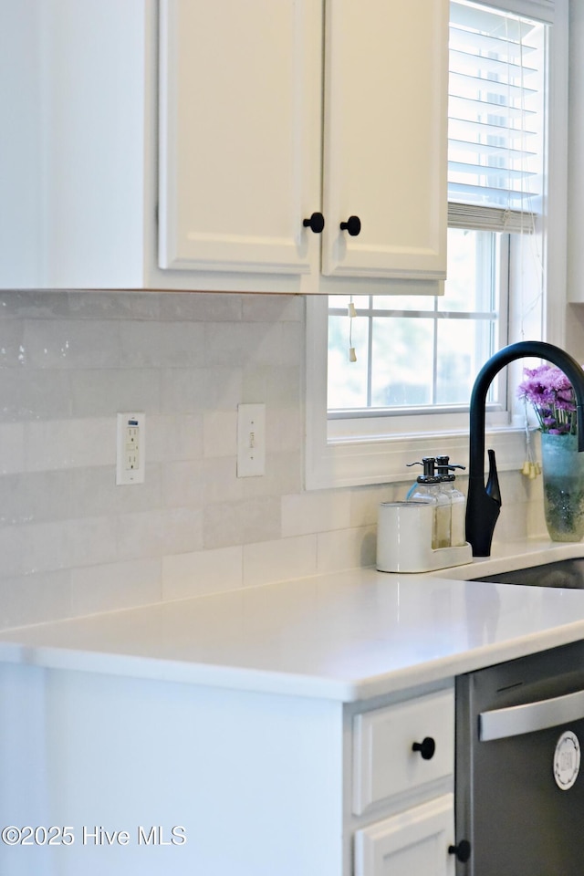 kitchen featuring backsplash, sink, white cabinets, and dishwasher