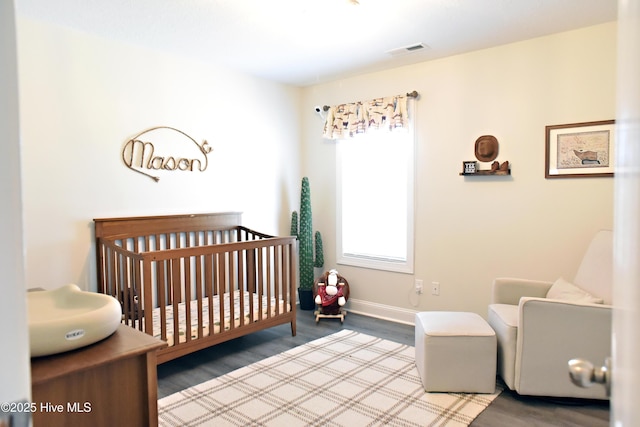 bedroom with wood-type flooring and a nursery area