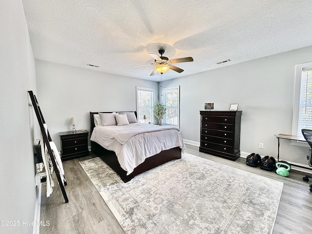 bedroom with multiple windows, wood-type flooring, and ceiling fan