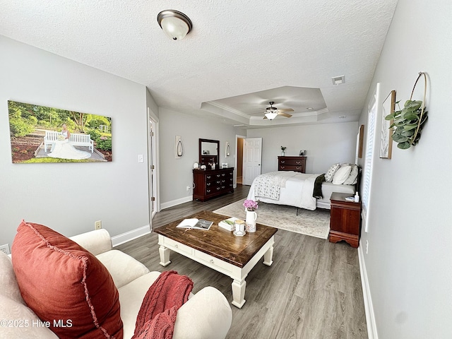 bedroom featuring a tray ceiling, wood-type flooring, a textured ceiling, and ceiling fan