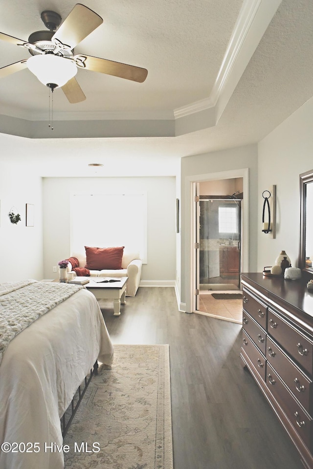 bedroom with crown molding, ceiling fan, hardwood / wood-style floors, a tray ceiling, and a textured ceiling