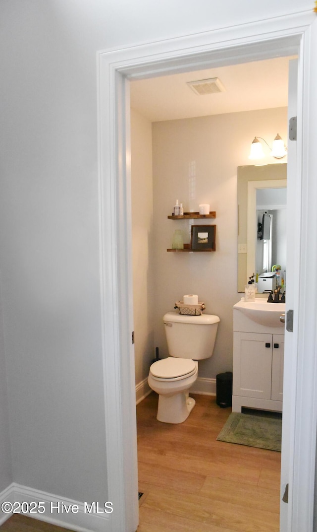 bathroom with hardwood / wood-style flooring, vanity, and toilet