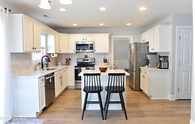 kitchen with stainless steel appliances, light hardwood / wood-style floors, sink, and a kitchen island