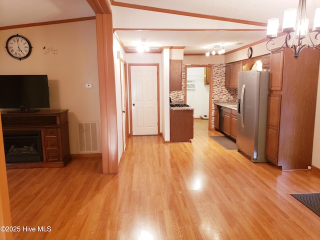 kitchen with tasteful backsplash, stainless steel fridge with ice dispenser, light hardwood / wood-style flooring, crown molding, and decorative light fixtures