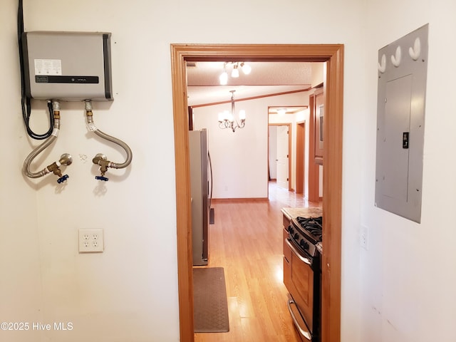 hallway featuring a textured ceiling, water heater, light hardwood / wood-style flooring, a notable chandelier, and electric panel