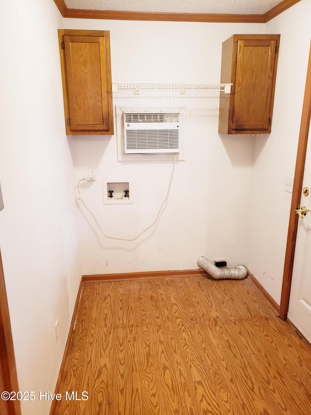 laundry area featuring cabinets, hookup for a washing machine, an AC wall unit, and ornamental molding