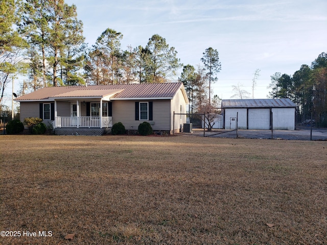 ranch-style house featuring a garage, a front yard, cooling unit, an outbuilding, and covered porch