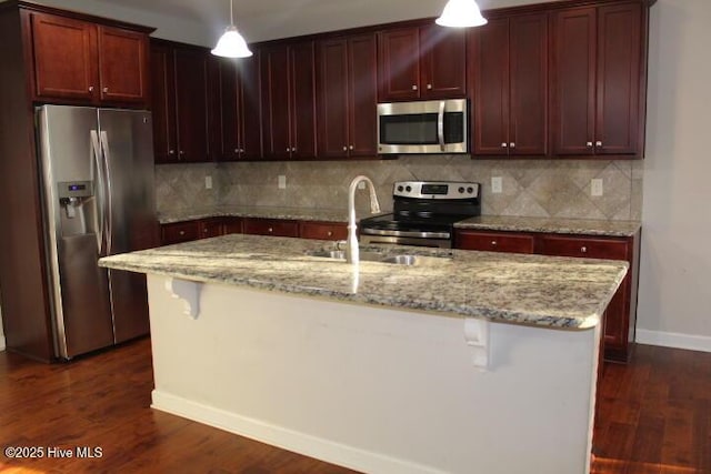 kitchen featuring a kitchen island with sink, a breakfast bar, hanging light fixtures, and appliances with stainless steel finishes