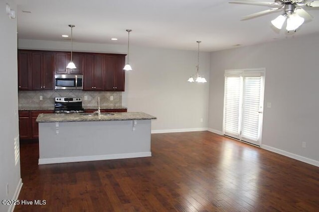 kitchen with appliances with stainless steel finishes, tasteful backsplash, a breakfast bar, sink, and pendant lighting