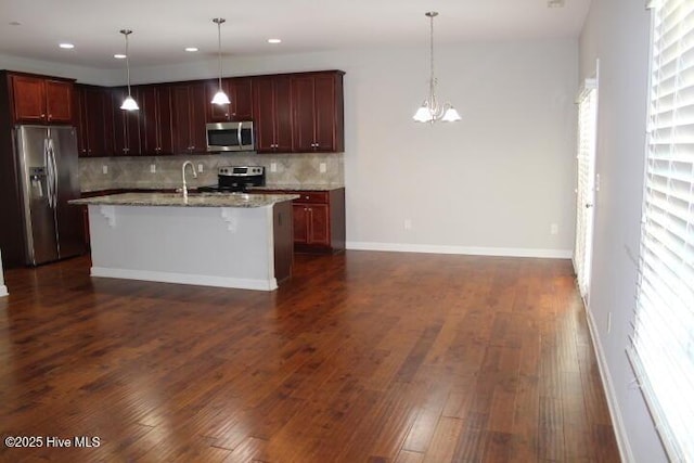 kitchen featuring a center island with sink, a breakfast bar, stainless steel appliances, and hanging light fixtures