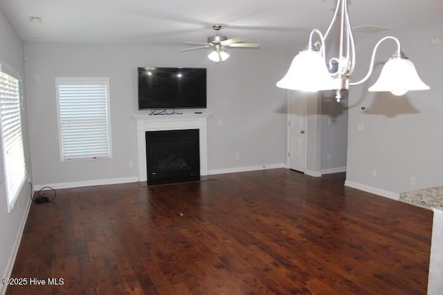 unfurnished living room featuring plenty of natural light, ceiling fan, and dark wood-type flooring