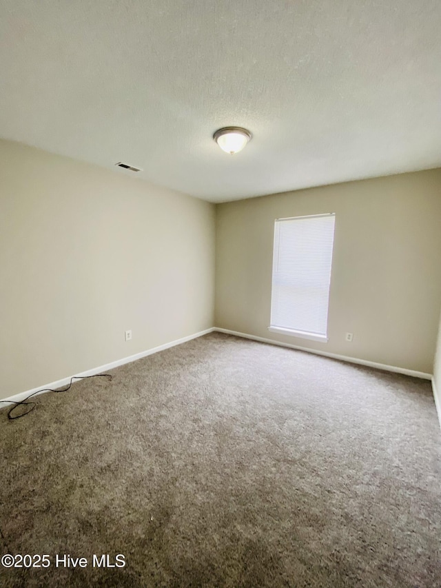 carpeted empty room featuring a textured ceiling