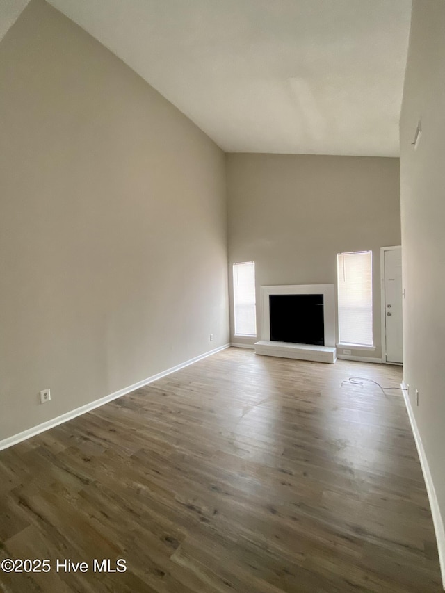 unfurnished living room with a high ceiling and dark wood-type flooring