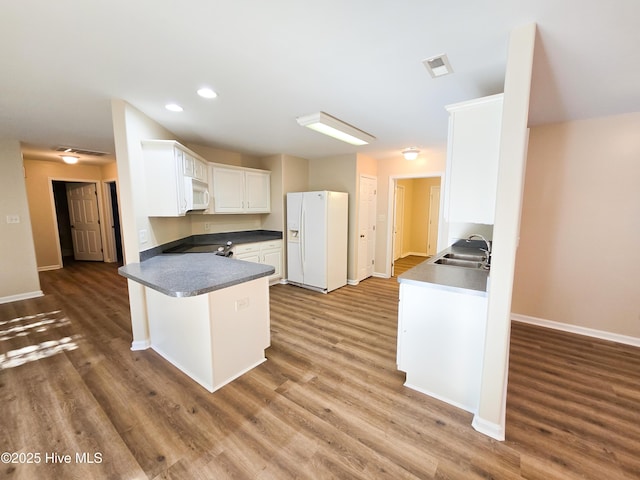 kitchen featuring sink, white cabinets, kitchen peninsula, dark wood-type flooring, and white appliances