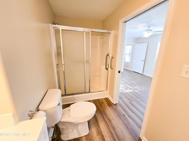 bathroom featuring toilet, vanity, a shower with door, hardwood / wood-style flooring, and ceiling fan