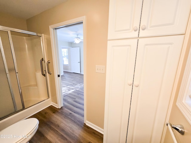 bathroom with toilet, an enclosed shower, and hardwood / wood-style floors