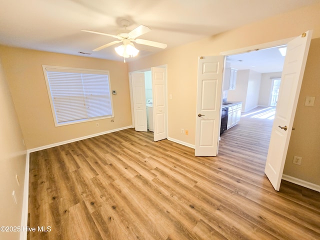 unfurnished bedroom featuring washer / clothes dryer, ceiling fan, and light wood-type flooring