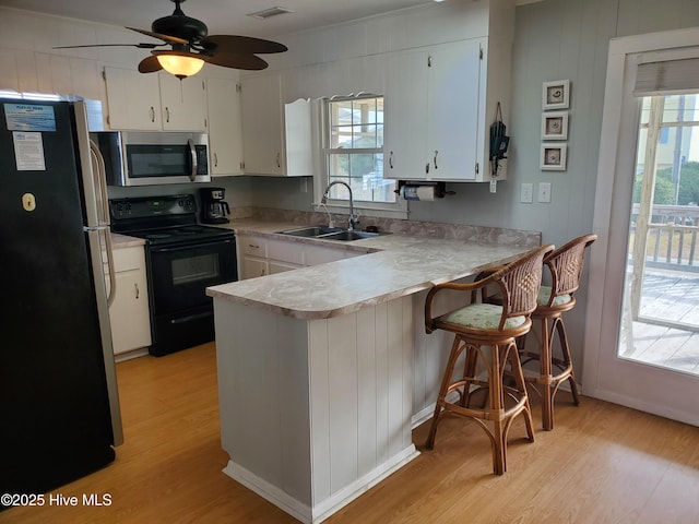 kitchen featuring sink, white cabinets, stainless steel appliances, and light hardwood / wood-style flooring