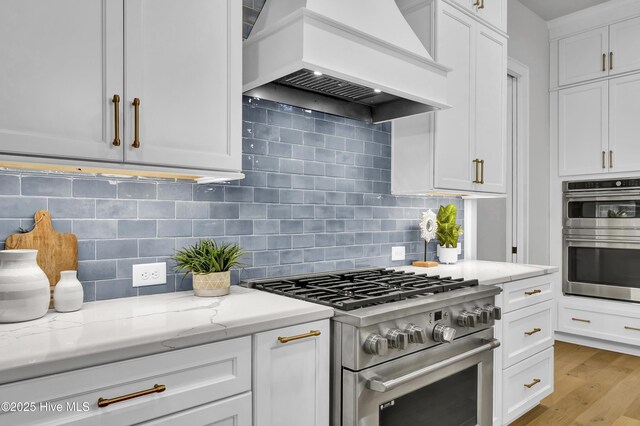 kitchen featuring a kitchen island with sink, sink, custom range hood, and white cabinets