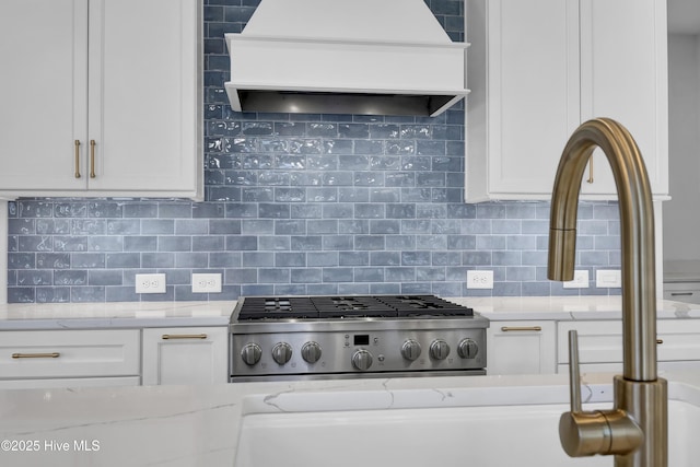 kitchen with light stone counters, white cabinetry, and premium range hood