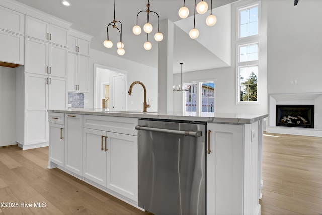 kitchen featuring dishwasher, pendant lighting, a center island with sink, and white cabinets