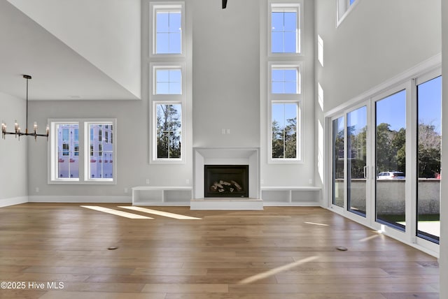 unfurnished living room with a high ceiling, wood-type flooring, and a chandelier