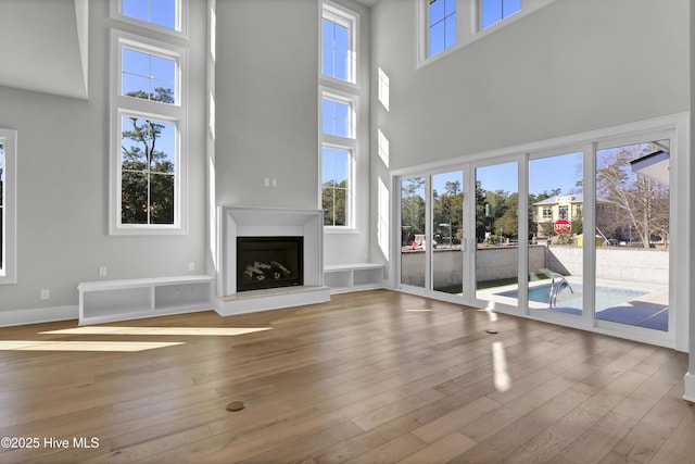 unfurnished living room featuring a high ceiling and light hardwood / wood-style floors