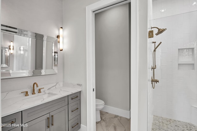 bathroom with tiled shower, vanity, and toilet