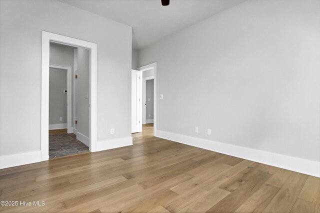 unfurnished bedroom featuring ceiling fan, ensuite bath, and light wood-type flooring