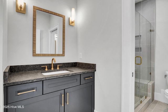 bathroom featuring tile patterned flooring, vanity, a shower with shower door, and toilet