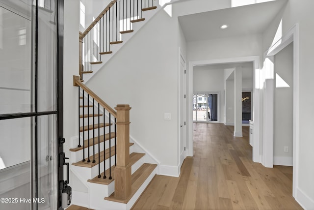 stairs featuring hardwood / wood-style flooring and a high ceiling