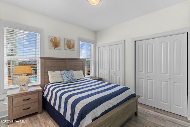 bedroom featuring light wood-type flooring and multiple closets