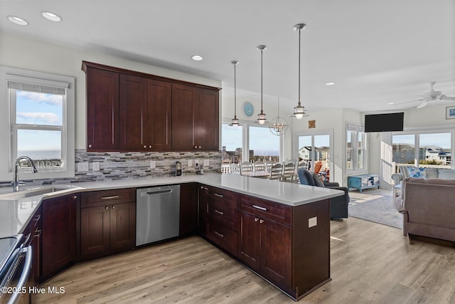 kitchen with a sink, open floor plan, a peninsula, appliances with stainless steel finishes, and light countertops