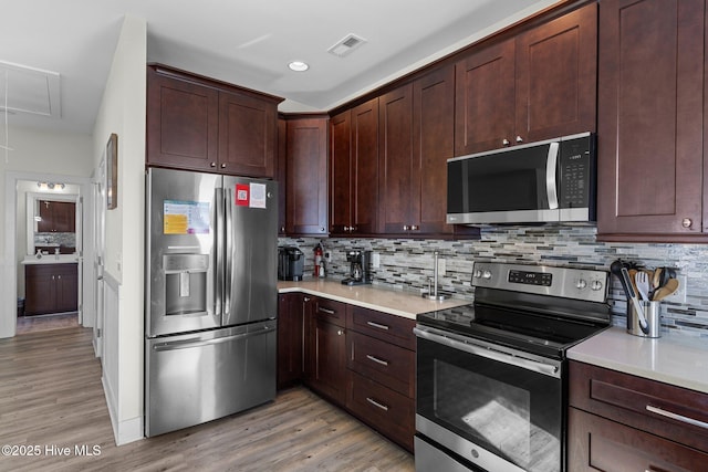 kitchen with visible vents, backsplash, light countertops, light wood-style flooring, and stainless steel appliances