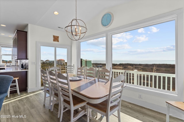 dining area with light wood-type flooring, an inviting chandelier, and a healthy amount of sunlight